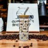 Glass cup with bamboo lid showing small thick flowers alternating with coffee beans.